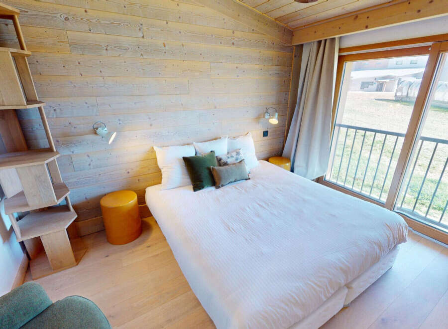 Experience cozy mountain living in this charming bedroom featuring a comfortable bed adorned with plush pillows and a unique wooden shelving unit.
