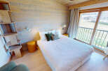 Experience cozy mountain living in this charming bedroom featuring a comfortable bed adorned with plush pillows and a unique wooden shelving unit.