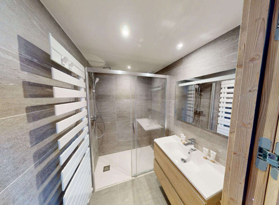 Experience modern comfort in this beautifully appointed bathroom, featuring a spacious glass-enclosed shower with sleek tile work and a convenient built-in bench.