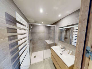 Experience modern comfort in this beautifully appointed bathroom, featuring a spacious glass-enclosed shower with sleek tile work and a convenient built-in bench.