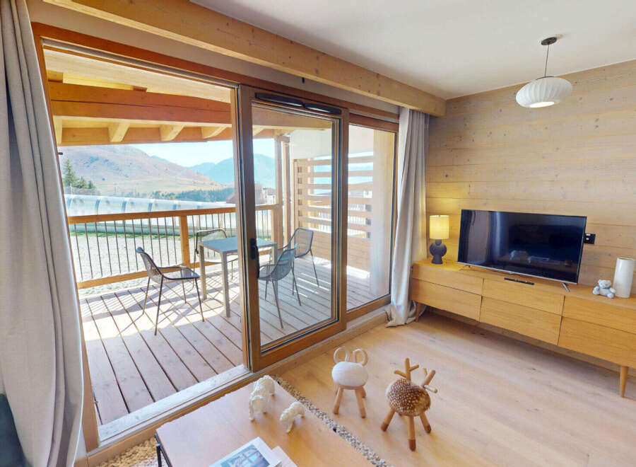 Experience mountain living in this charming apartment featuring a spacious living area with a modern entertainment center and a cozy balcony perfect for enjoying the scenic views.