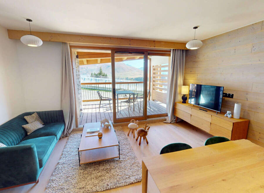 Experience modern mountain living in this beautifully appointed living space, featuring a plush teal sofa and a rustic wooden entertainment center.