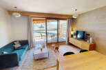 Experience modern mountain living in this beautifully appointed living space, featuring a plush teal sofa and a rustic wooden entertainment center.