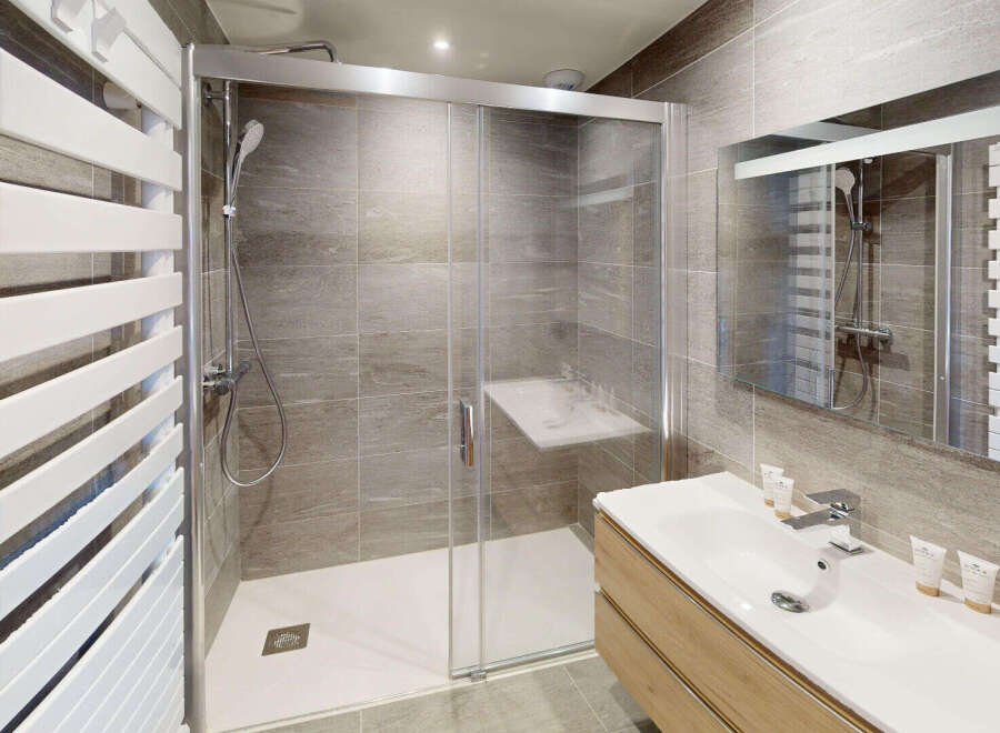 Experience modern comfort in this beautifully appointed bathroom, featuring a spacious walk-in shower with a built-in seat and sleek glass enclosure.