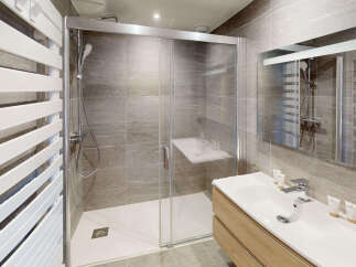Experience modern comfort in this beautifully appointed bathroom, featuring a spacious walk-in shower with a built-in seat and sleek glass enclosure.