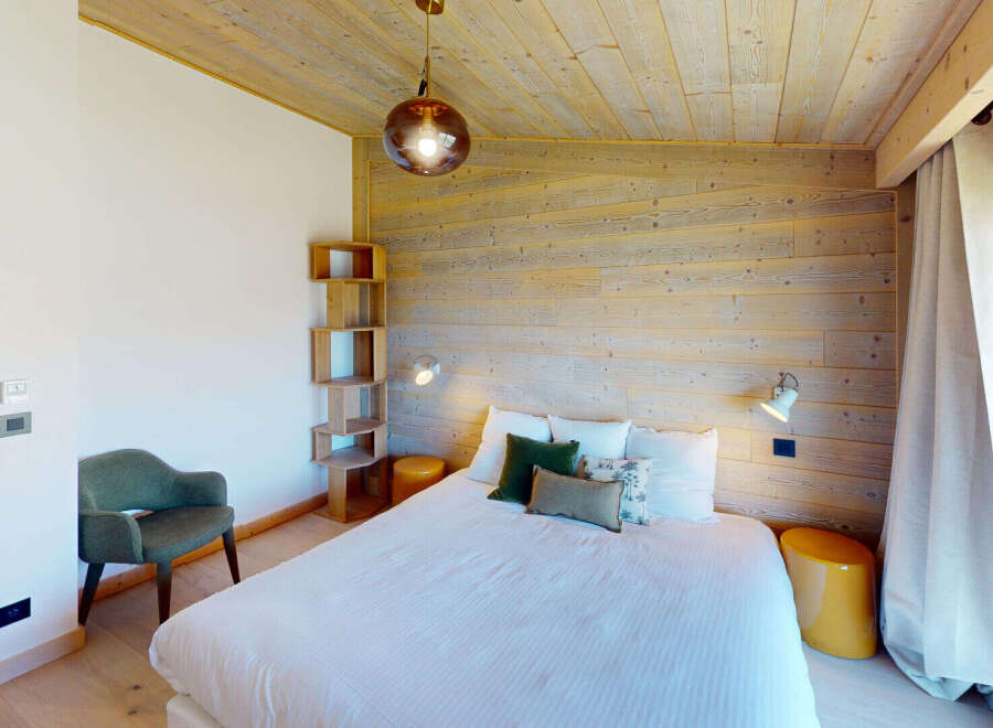 Experience cozy mountain living in this charming bedroom featuring a comfortable bed adorned with plush pillows and a stylish accent chair.