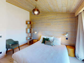 Experience cozy mountain living in this charming bedroom featuring a comfortable bed adorned with plush pillows and a stylish accent chair.