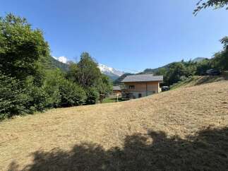 Experience the charm of mountain living in this picturesque property featuring a modern wooden chalet nestled amidst lush greenery.