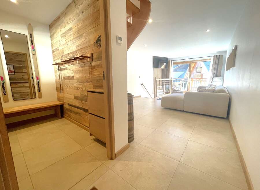 Step into a charming mountain retreat featuring a rustic wooden accent wall and a convenient bench with ski storage.