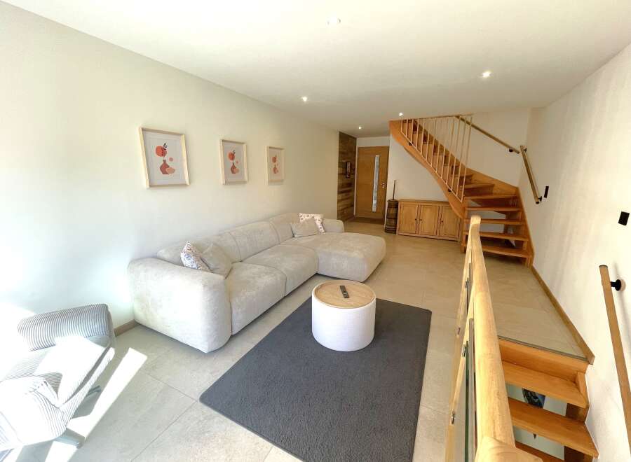 Experience modern living in this spacious living area featuring a comfortable sectional sofa and a stylish round ottoman coffee table.