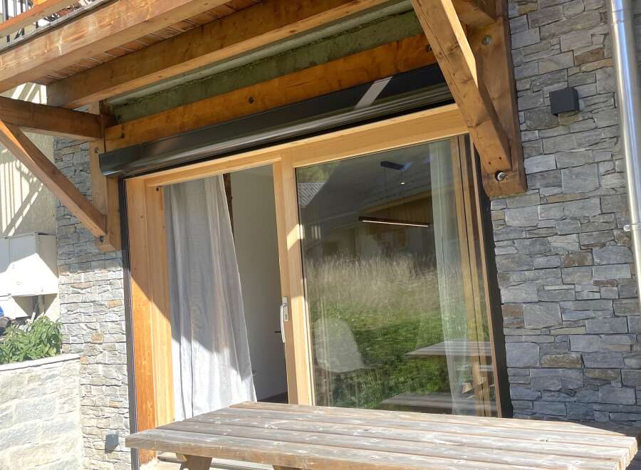 Enjoy outdoor living with this charming property featuring a rustic wooden picnic table on a stone patio, perfect for al fresco dining.