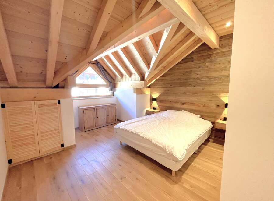 Experience cozy living in this charming attic bedroom, featuring a beautifully crafted wooden ceiling and walls that exude rustic warmth.