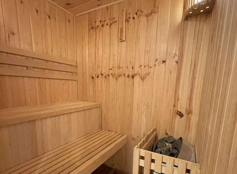 Experience ultimate relaxation in this beautifully crafted wooden sauna, featuring comfortable tiered seating perfect for unwinding.