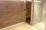 Experience ultimate relaxation in this modern spa area, featuring a private sauna with natural wood interiors and a sleek, spacious shower enclosure.