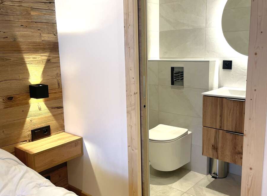 Experience modern comfort in this beautifully appointed bedroom featuring a rustic wooden accent wall and a sleek, integrated nightstand.