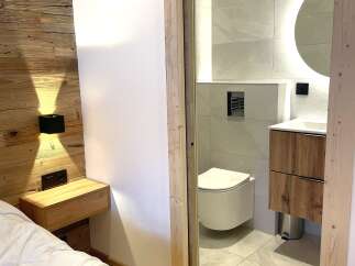 Experience modern comfort in this beautifully appointed bedroom featuring a rustic wooden accent wall and a sleek, integrated nightstand.