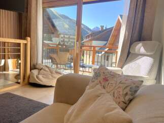 Experience breathtaking mountain views from this cozy living space, featuring a comfortable armchair and a plush beanbag chair perfect for relaxation.