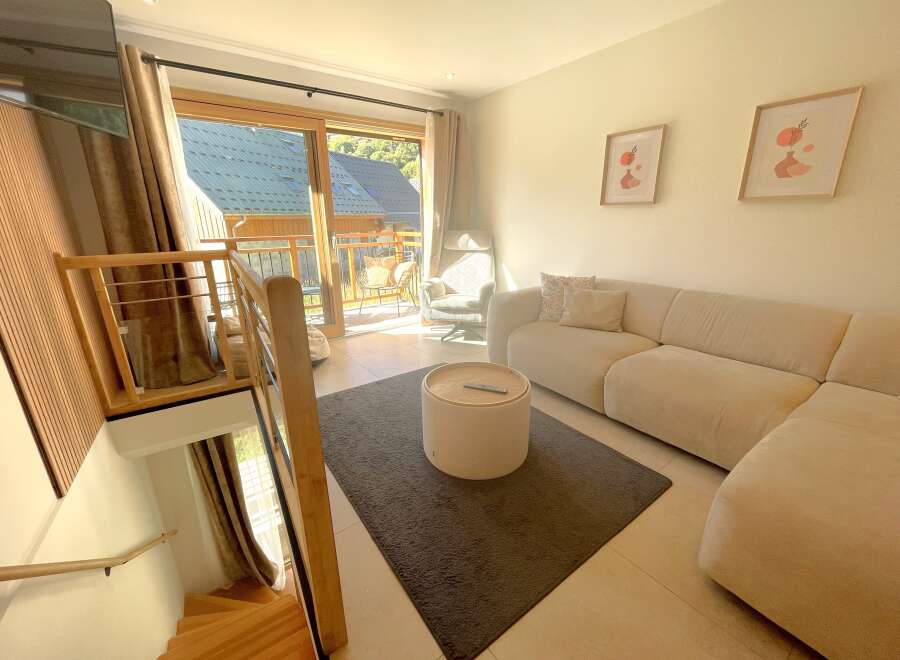 Experience modern living in this beautifully appointed apartment, featuring a spacious living area with a plush sectional sofa and a stylish round coffee table.