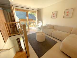 Experience modern living in this beautifully appointed apartment, featuring a spacious living area with a plush sectional sofa and a stylish round coffee table.