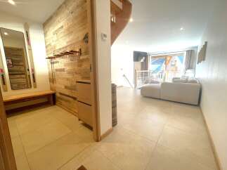 Step into a charming mountain retreat featuring a rustic wooden accent wall and a convenient bench with ski storage.