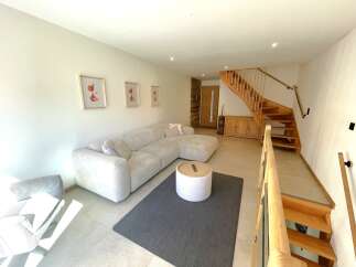 Experience modern living in this spacious living area featuring a comfortable sectional sofa and a stylish round ottoman coffee table.