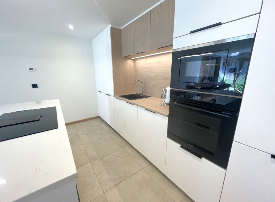 Discover this modern kitchen featuring sleek white cabinetry and warm wood accents.