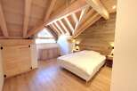 Experience cozy living in this charming attic bedroom, featuring a beautifully crafted wooden ceiling and walls that exude rustic warmth.