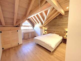 Experience cozy living in this charming attic bedroom, featuring a beautifully crafted wooden ceiling and walls that exude rustic warmth.