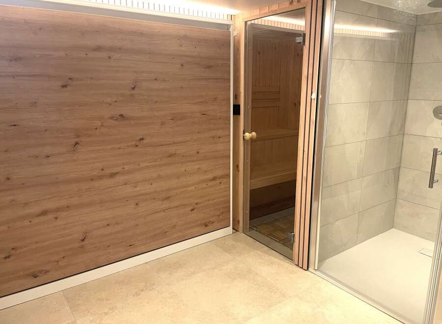 Experience ultimate relaxation in this modern spa area, featuring a private sauna with natural wood interiors and a sleek, spacious shower enclosure.