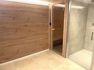Experience ultimate relaxation in this modern spa area, featuring a private sauna with natural wood interiors and a sleek, spacious shower enclosure.