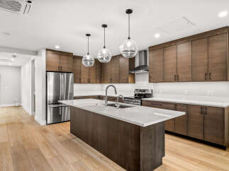 Experience modern living in this stunning kitchen featuring sleek, dark wood cabinetry and a spacious island with a waterfall countertop.