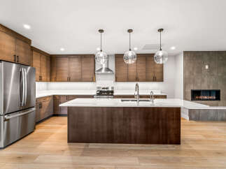 Experience modern luxury in this stunning kitchen featuring sleek, dark wood cabinetry and a spacious island with a waterfall countertop.