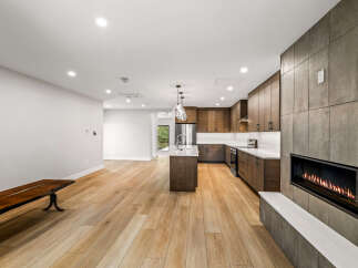 Experience modern living in this stunning open-concept space featuring a sleek kitchen with dark wood cabinetry and a central island.