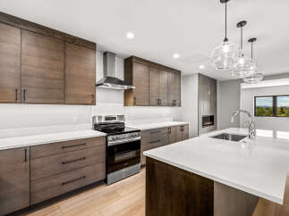 Experience modern luxury in this stunning kitchen, featuring sleek dark wood cabinetry and pristine white quartz countertops.