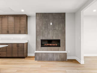 Experience modern living with this stunning interior featuring a sleek gas fireplace as the focal point, surrounded by contemporary tilework.