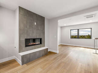 Experience modern living with this stunning fireplace, featuring a sleek tile surround and a built-in bench.