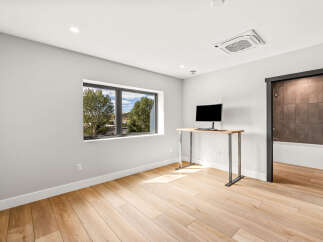 Discover modern living in this bright and airy room featuring a large window with scenic views and a sleek standing desk with a monitor.