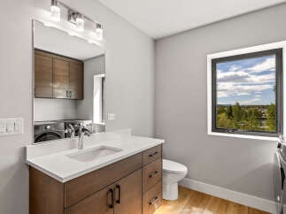 Discover modern convenience in this stylish laundry room, featuring a sleek vanity with a quartz countertop and ample storage.