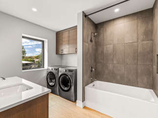This modern bathroom features a sleek white vanity with a chrome faucet, complemented by a spacious soaking tub and a separate shower area with elegant tilework.