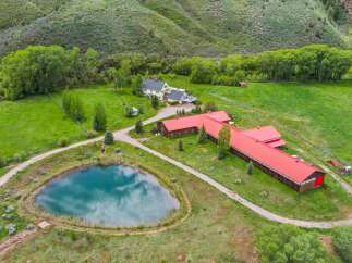 Discover this expansive ranch property featuring a charming yellow farmhouse with a wraparound deck, perfect for enjoying the serene mountain views.