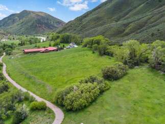 Discover this expansive property nestled in a picturesque valley, featuring a charming farmhouse and extensive red barns perfect for equestrian or agricultural pursuits.