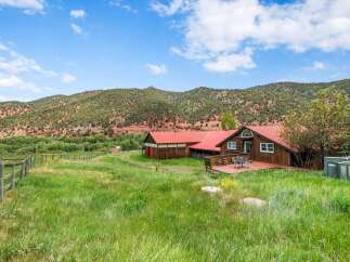 Experience serene country living with this charming property featuring a spacious home and barn, nestled against a backdrop of majestic mountains.