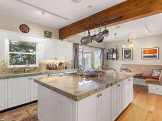 This spacious kitchen boasts a large granite island with a built-in stovetop, perfect for meal preparation and casual dining.