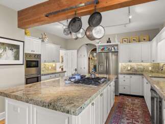 Experience culinary excellence in this stunning kitchen, featuring a spacious granite island with a built-in gas range and ample seating.