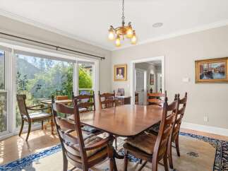 This elegant dining room features a large wooden table surrounded by classic wooden chairs, perfect for hosting family gatherings.