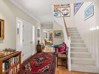 Step into this charming entryway featuring a beautiful Persian rug and a wooden bookshelf filled with books and a chess set.