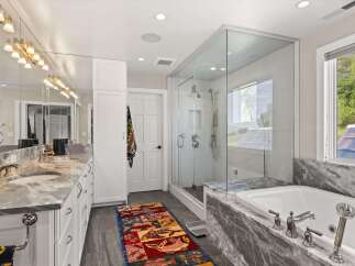 Indulge in luxury with this stunning master bathroom, featuring a spacious walk-in shower with a rainfall showerhead and a deep soaking tub perfect for relaxation.