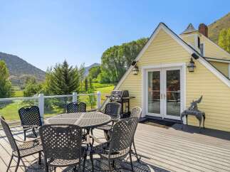 Enjoy breathtaking mountain views from this charming yellow home's expansive deck, perfect for outdoor dining and entertaining.