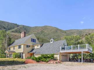 Nestled against a backdrop of rolling hills, this charming yellow home offers a serene retreat.