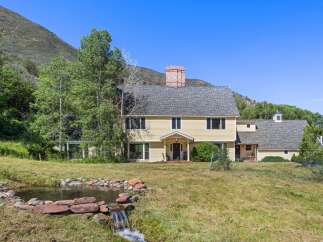 Nestled against a scenic mountain backdrop, this charming yellow home offers a tranquil retreat.